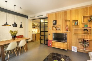 Ein modernes Wohnzimmer mit einer Wandverkleidung aus Holz, einem Essbereich mit Holztisch und Stühlen sowie einer TV-Konsole mit Flachbildfernseher.