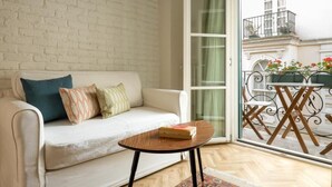 A living room with a white sofa, a small round table, and a glass door leading to an outdoor balcony with a table and chairs. - Pera Neuf (Istanbul)