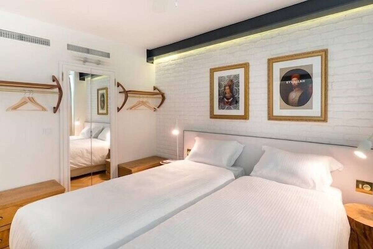 A bedroom with a large bed, bedside tables, a wardrobe, and two framed pictures on the wall.
