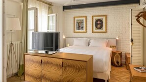 A bedroom with a bed, a wooden dresser, a television on the dresser, a ceiling fan, and two framed pictures on the wall. - Pera Neuf (Istanbul)