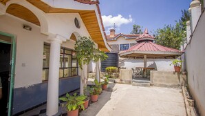A courtyard with potted plants, a covered seating area, and a building with a tiled roof. - Nairobi Airport Rest House (Nairobi)