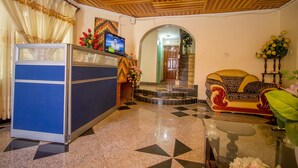 A reception area with a blue counter, a television, and a sofa with patterned cushions. - Nairobi Airport Rest House (Nairobi)