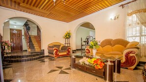 A spacious lobby with a grand staircase, a sofa, and a coffee table with flowers. - Nairobi Airport Rest House (Nairobi)