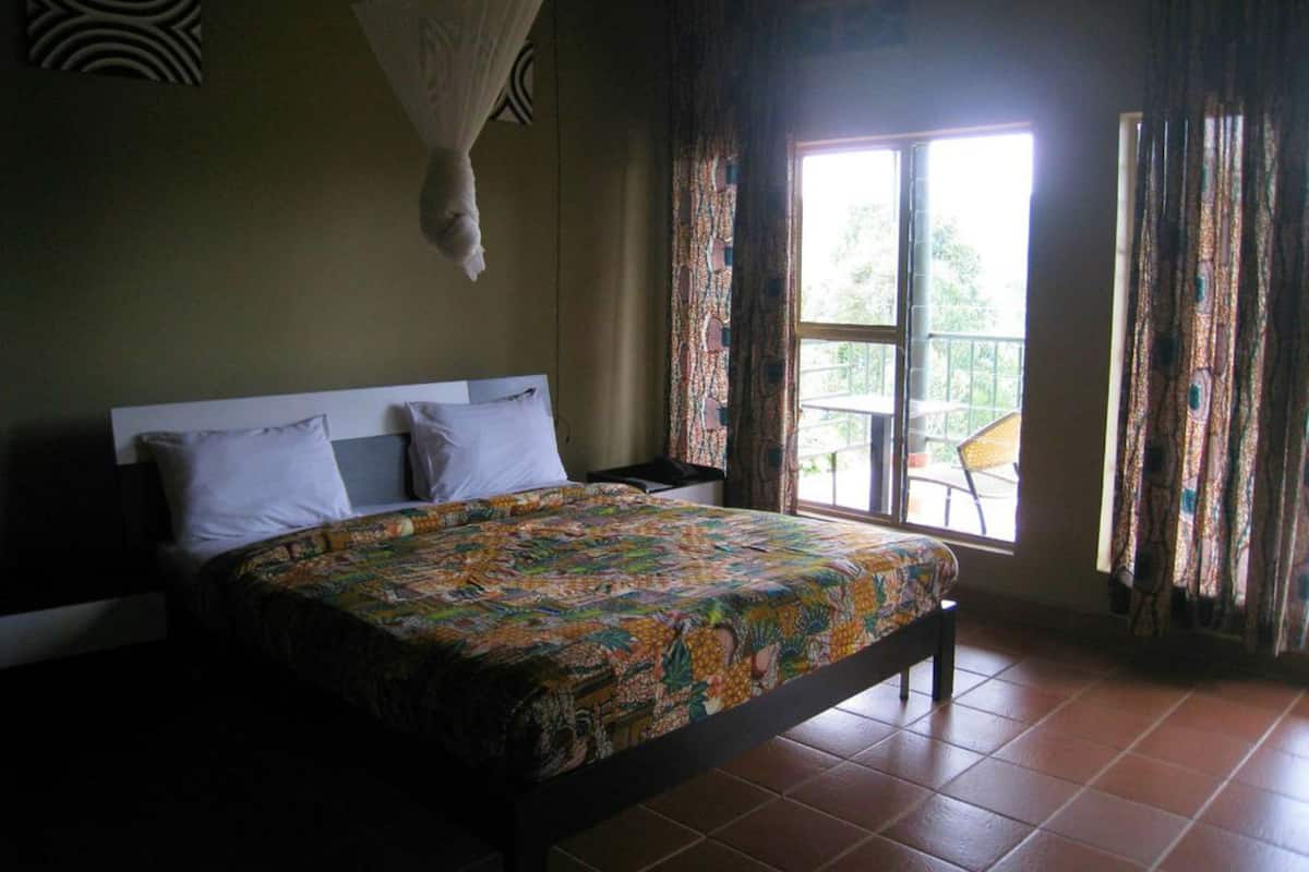 A bedroom with a bed, curtains, a window, and a hanging mosquito net.