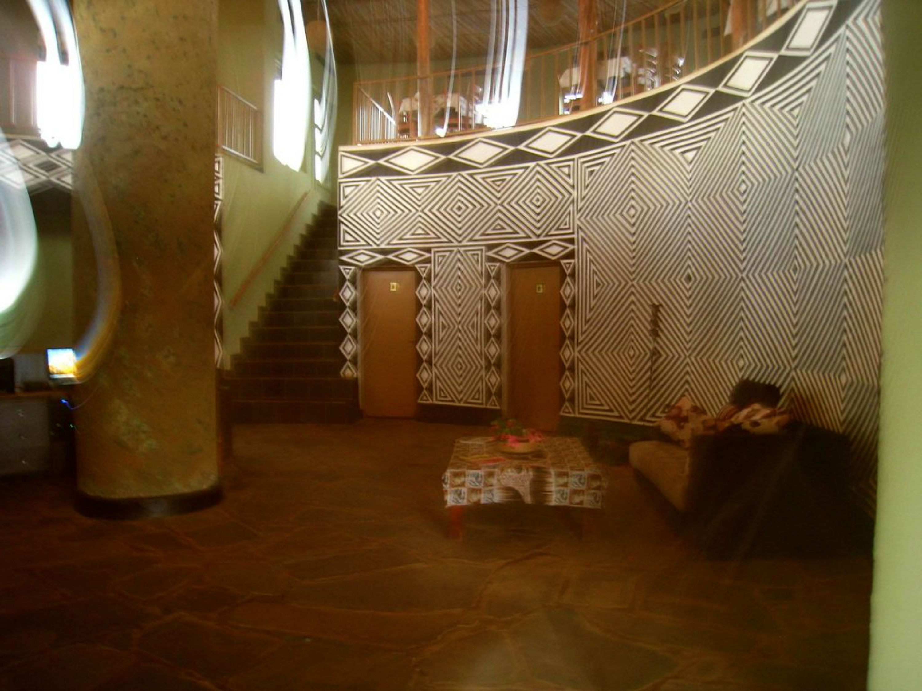 Un vestíbulo con una escalera, paredes con diseños y un mostrador de recepción.