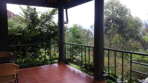 Un espacio al aire libre cubierto con suelo de baldosas, baranda metálica y una silla de mimbre.