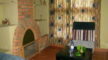 Una habitación acogedora con chimenea de ladrillo, un papel tapiz decorativo y una pequeña mesa con una planta.
