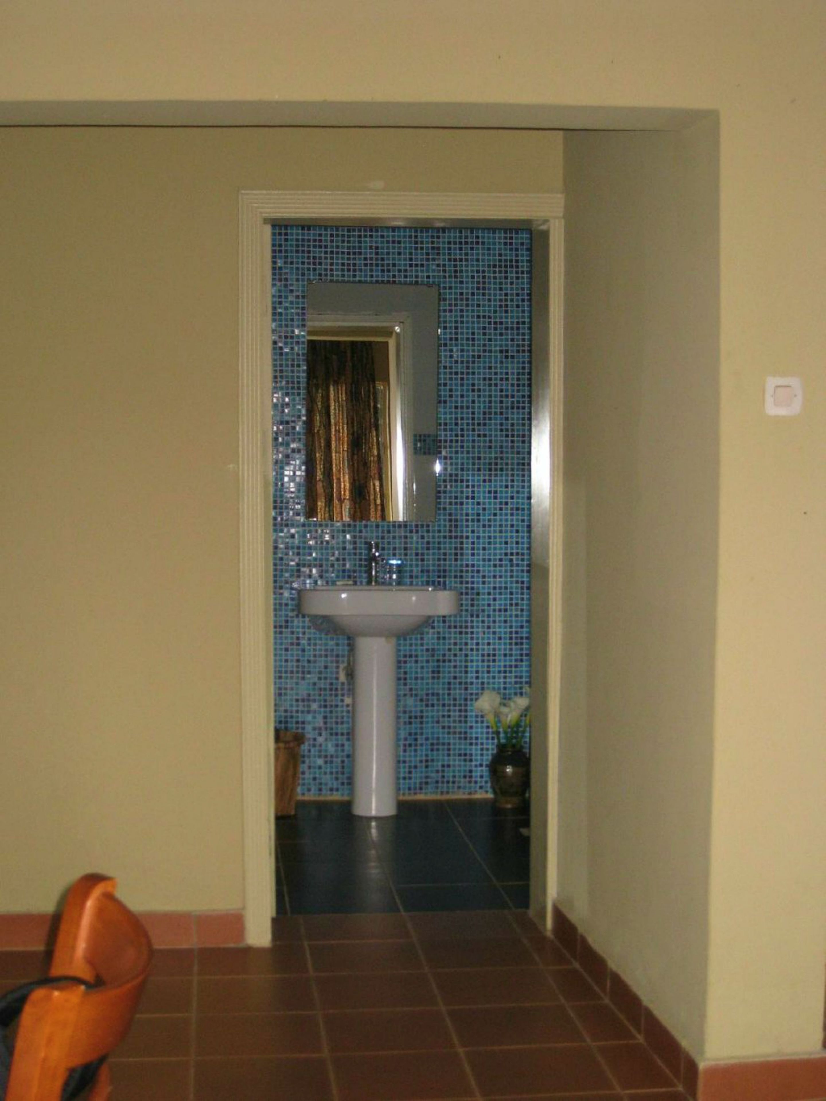 A bathroom with a tiled wall, a sink, and a mirror.