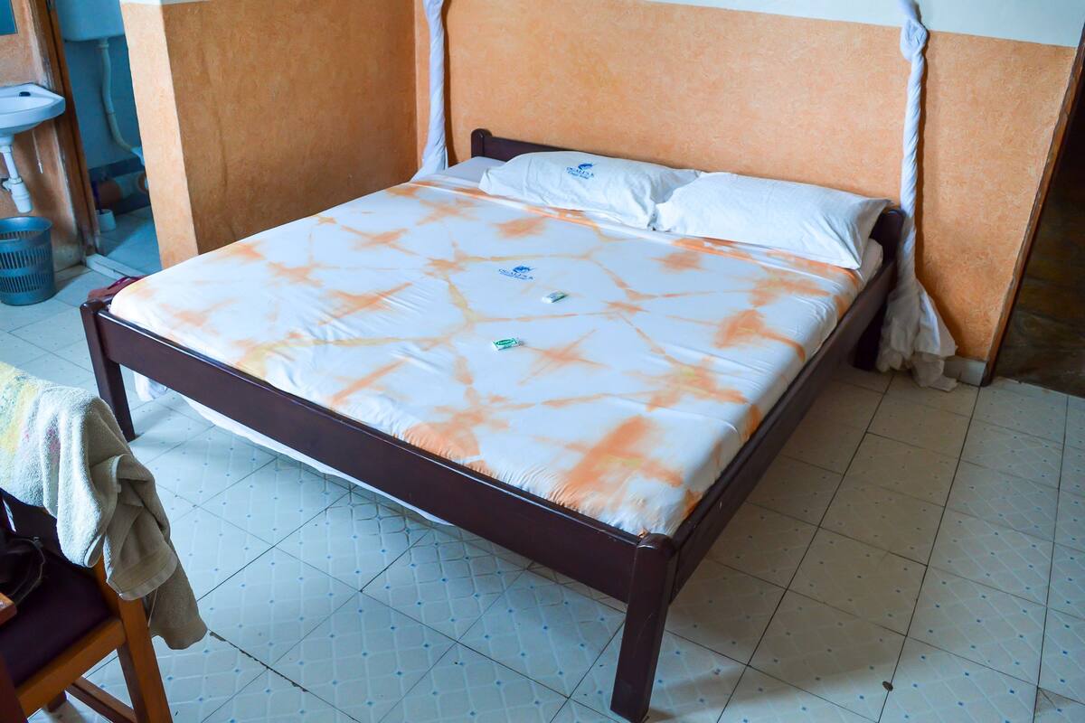 Een bed met een bed met een patroon, een houten hoofdbord en een betegelde vloer.