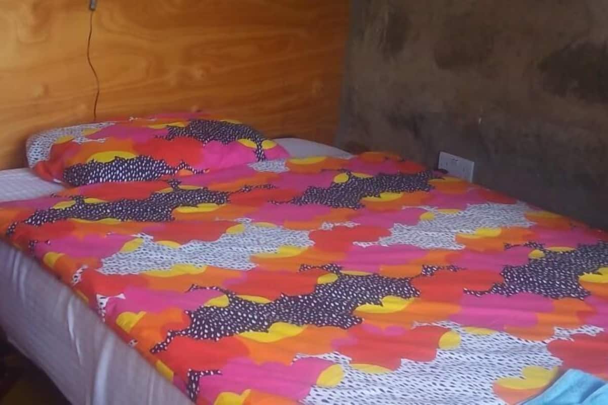 A small, single-bed room with a wooden headboard and a colorful bedspread.
