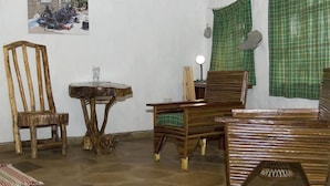 A room with a wooden chair, a small round table, and a sofa. - Oloolua Resort & Campground (Ngong)