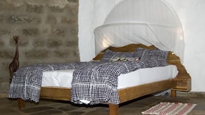 A bed with a canopy, checkered bedding, and a rustic wooden headboard. - Oloolua Resort & Campground (Ngong)