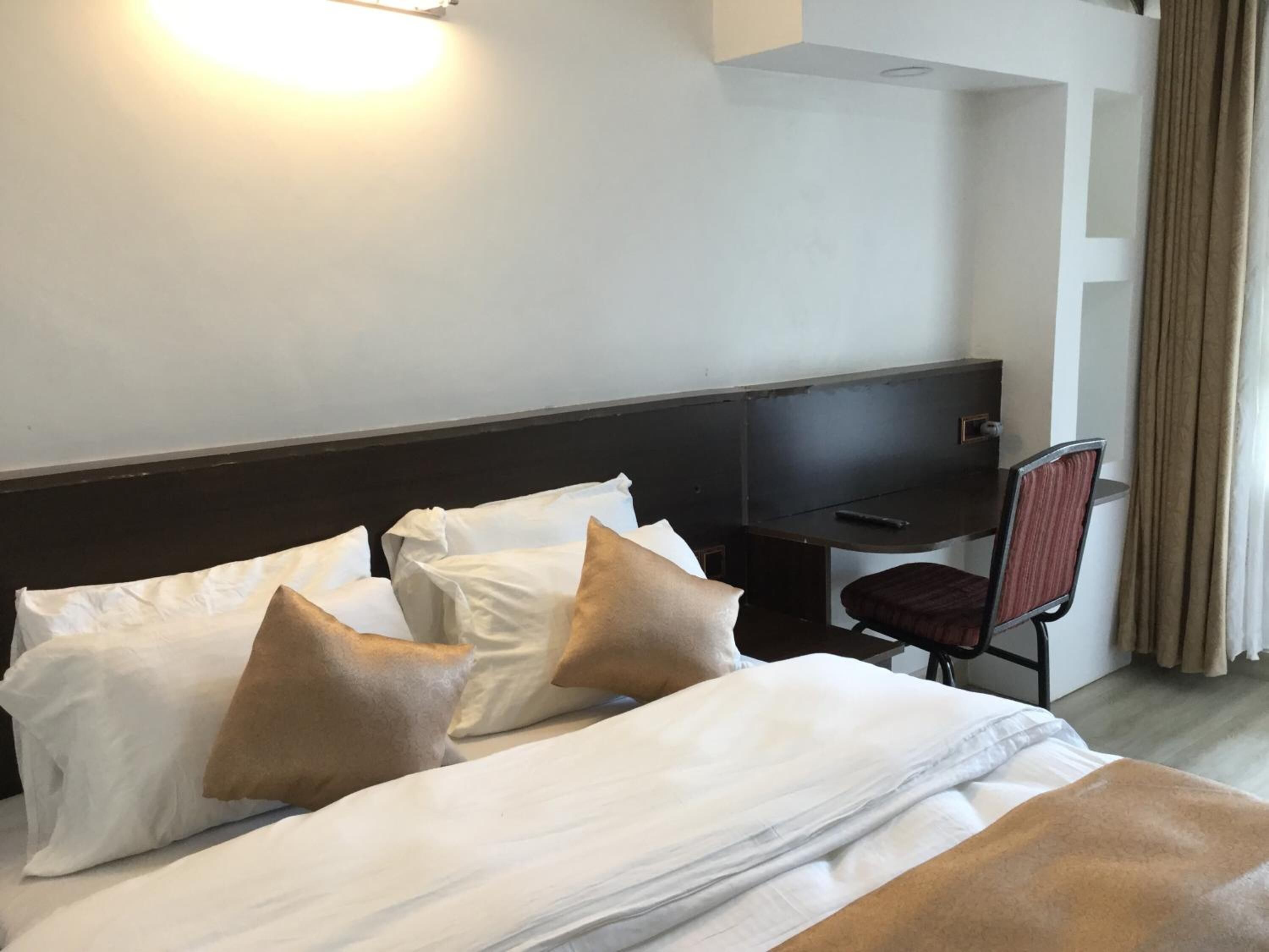 Une chambre d’hôtel équipée d’un lit, d’oreillers, d’un bureau, d’une chaise et d’un téléviseur.