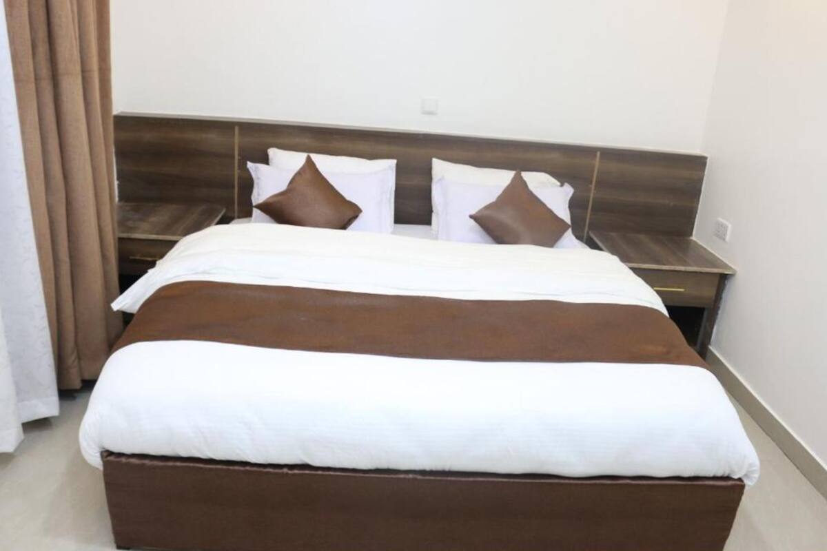 Ein Hotelzimmer mit einem großen Bett, einem Holzkopfstück und einem Nachttisch mit einer Lampe.