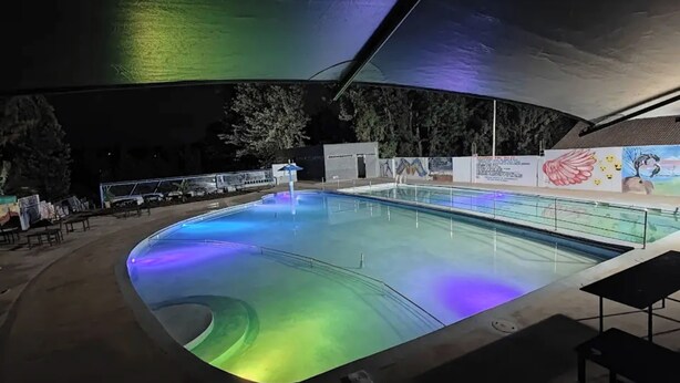 An indoor swimming pool with a curved design, surrounded by a covered area with a mural. - Oriental Palace Hotel (Embu)