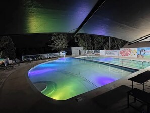 An indoor swimming pool with a curved design, surrounded by a covered area with a mural. - Oriental Palace Hotel (Embu)