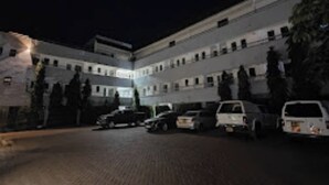 A multi-story building with a courtyard. There are several parked cars and a few people visible. - Oriental Palace Hotel (Embu)