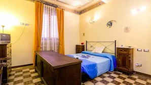 Une chambre à coucher comprenant un lit, un bureau, une télévision et une armoire.