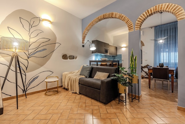 Una sala de estar moderna con un sofá, una zona de comedor y una cocina al fondo.