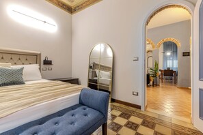 Una habitación de hotel moderna con una cama grande, un banco, un espejo y vista al comedor.
