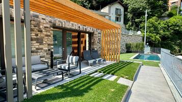 Relax in a serene outdoor space with lounge chairs and a small table, adjacent to a pool and beautifully manicured grounds.