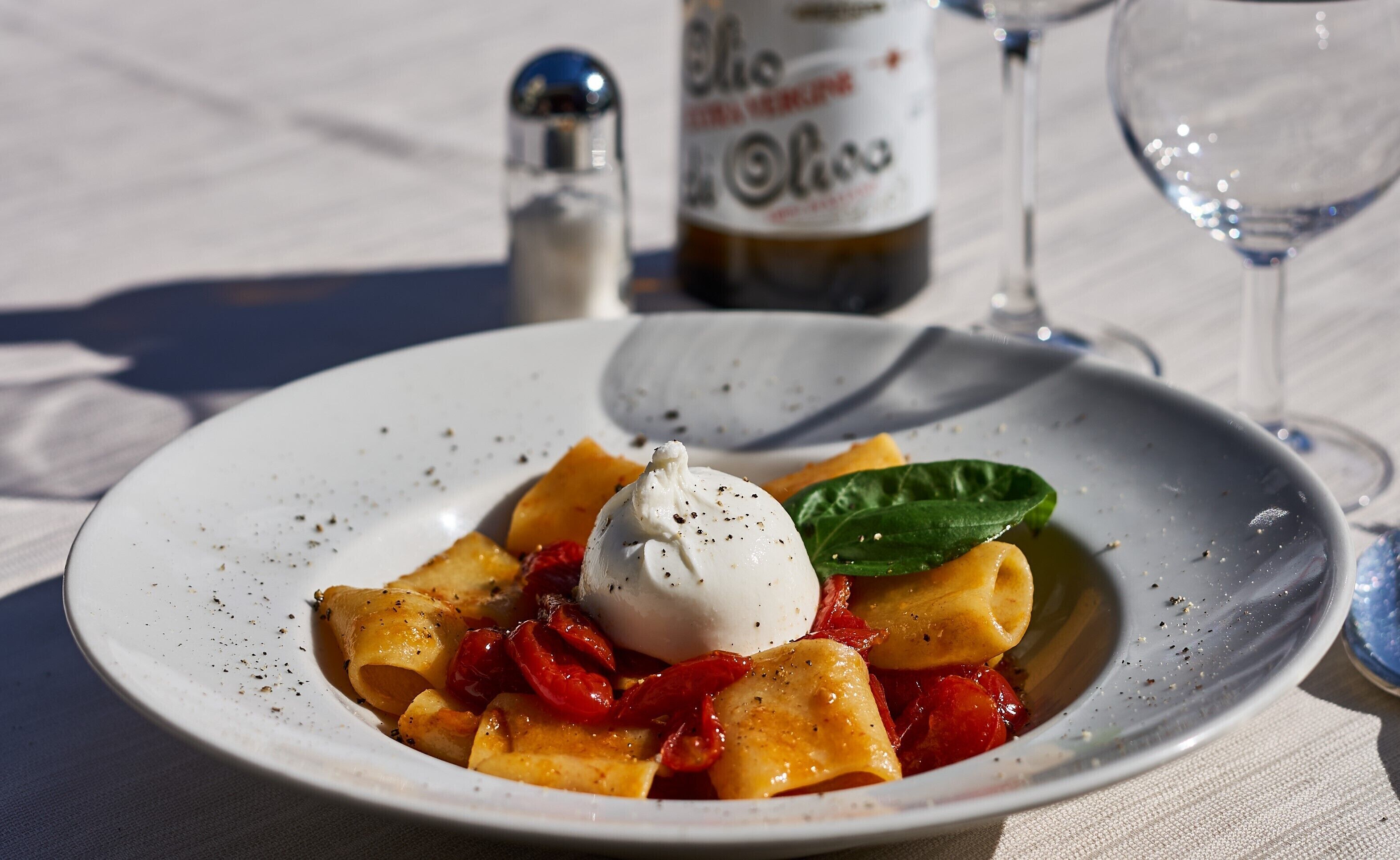 Une assiette de pâtes, nappée d’une cuillerée de sauce et garnie d’une feuille de basilic.