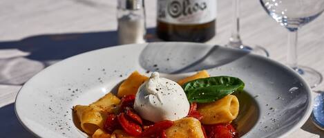 A plate of pasta with a dollop of sauce and a basil leaf.