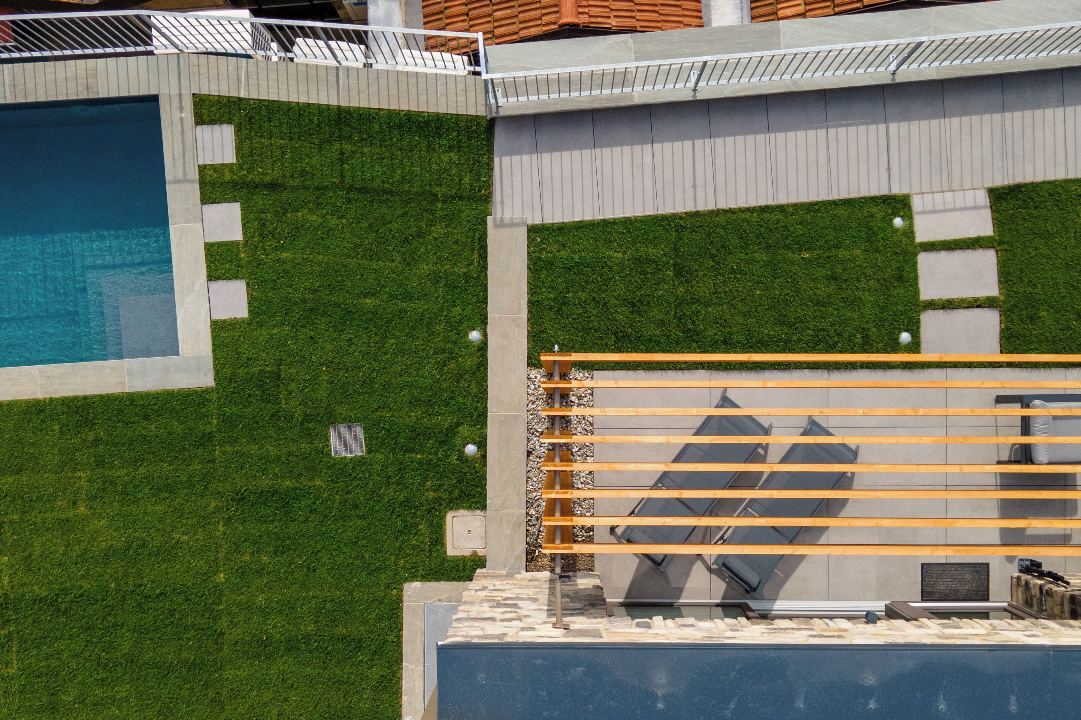 Um edifício moderno com piscina, área de pátio com assentos e gramado bem cuidado.