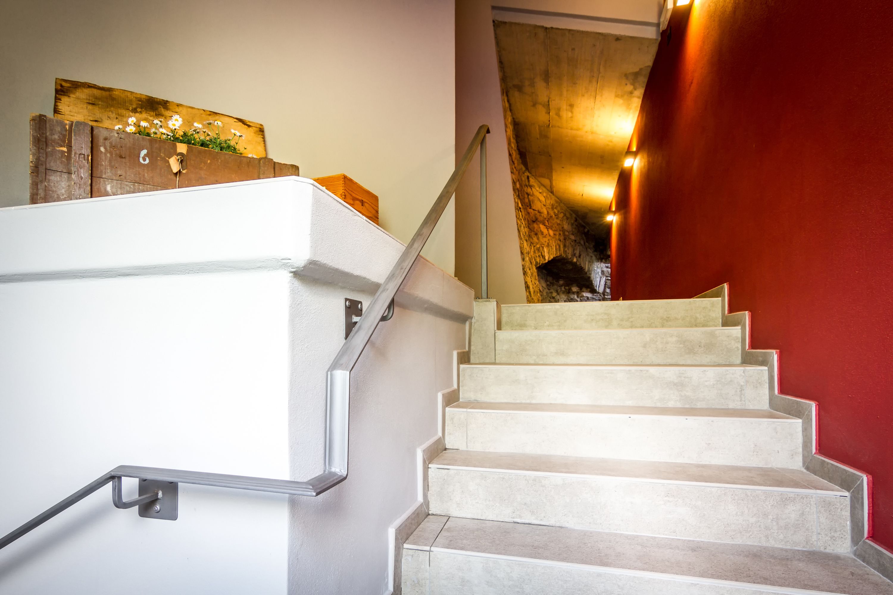 Een trap met een leuning en een houten wand met bloemstuk.
