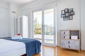 A bedroom with a bed, a wardrobe, a dresser, and a balcony with a view. - EV Apartments (Serik)