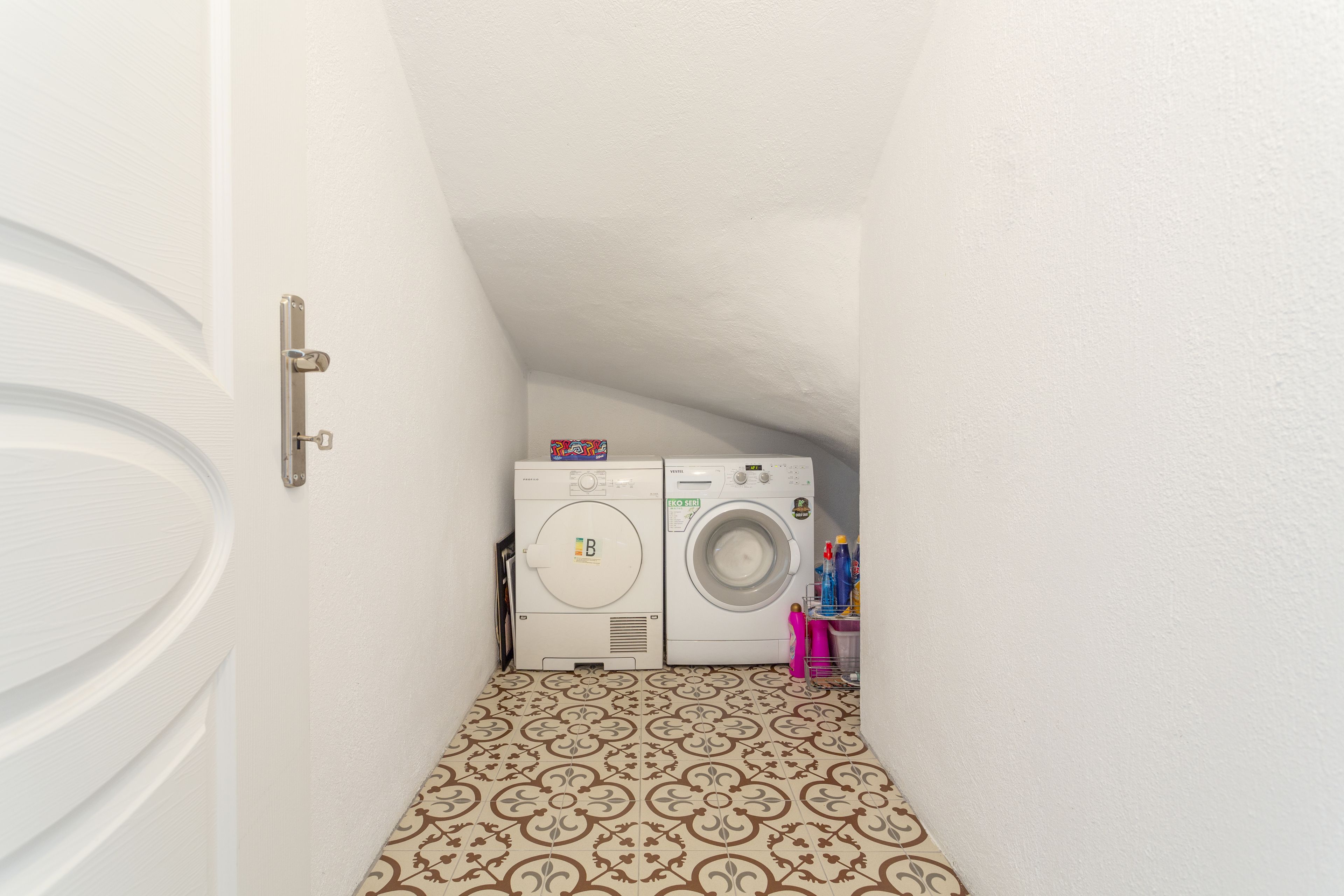 Un cuarto de lavado con lavadora y secadora, piso estampado y una puerta.