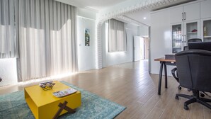A modern living room with a yellow coffee table, a blue rug, and a black office chair. - EV Apartments (Serik)