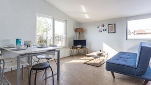 A modern living room with a dining area, a sofa, and a TV on a stand. - EV Apartments (Serik)
