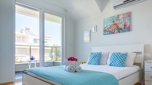 A bedroom with a bed, a window, and a painting on the wall. - EV Apartments (Serik)