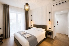 A hotel room with a large bed, bedside tables, a hanging light fixture, and a door with a lock. - Avec Moi Roma (Rome)