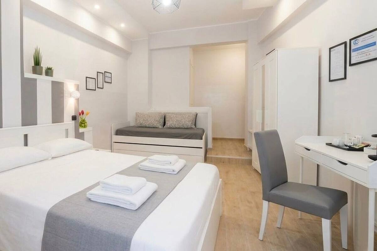 A modern hotel room with a large bed, a desk, and a chair.