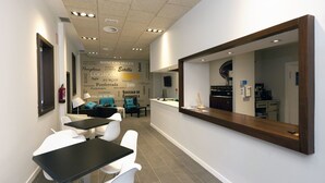 Uma clínica dentária moderna com área de receção, sala de espera com cadeiras e mesas, e uma cozinha visível.