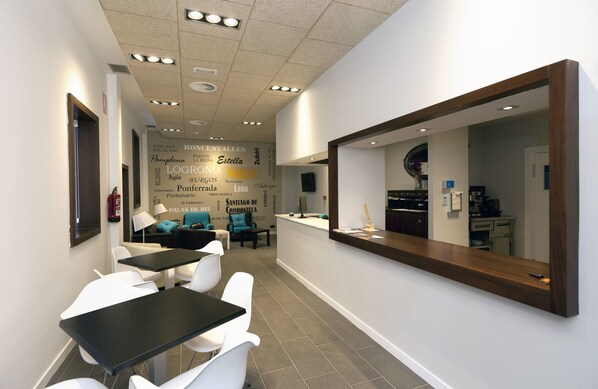 A modern dental clinic with a reception area, a waiting area with chairs and tables, and a visible kitchen area. - Hostal Hispano (Najera)