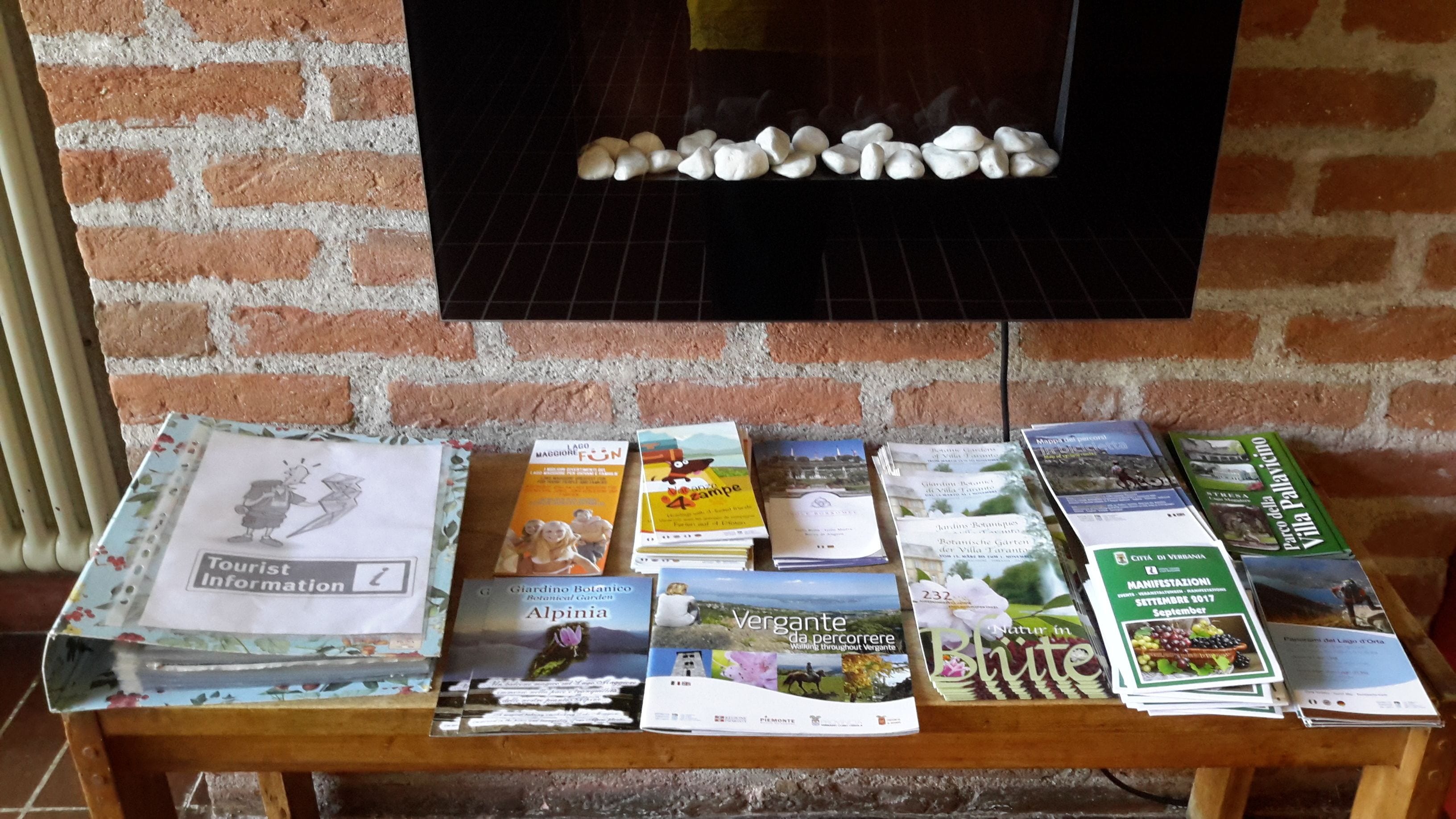 A table with brochures and a brick wall in the background.