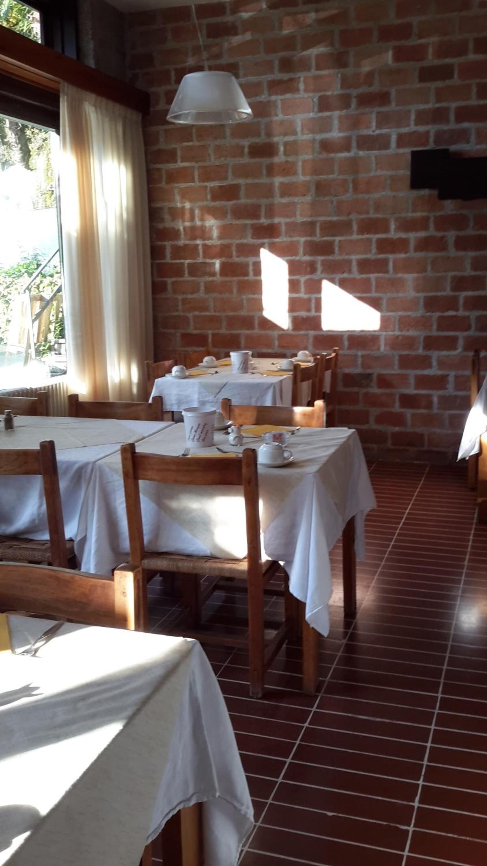 A dining area with brick walls, white tablecloths, and wooden chairs.