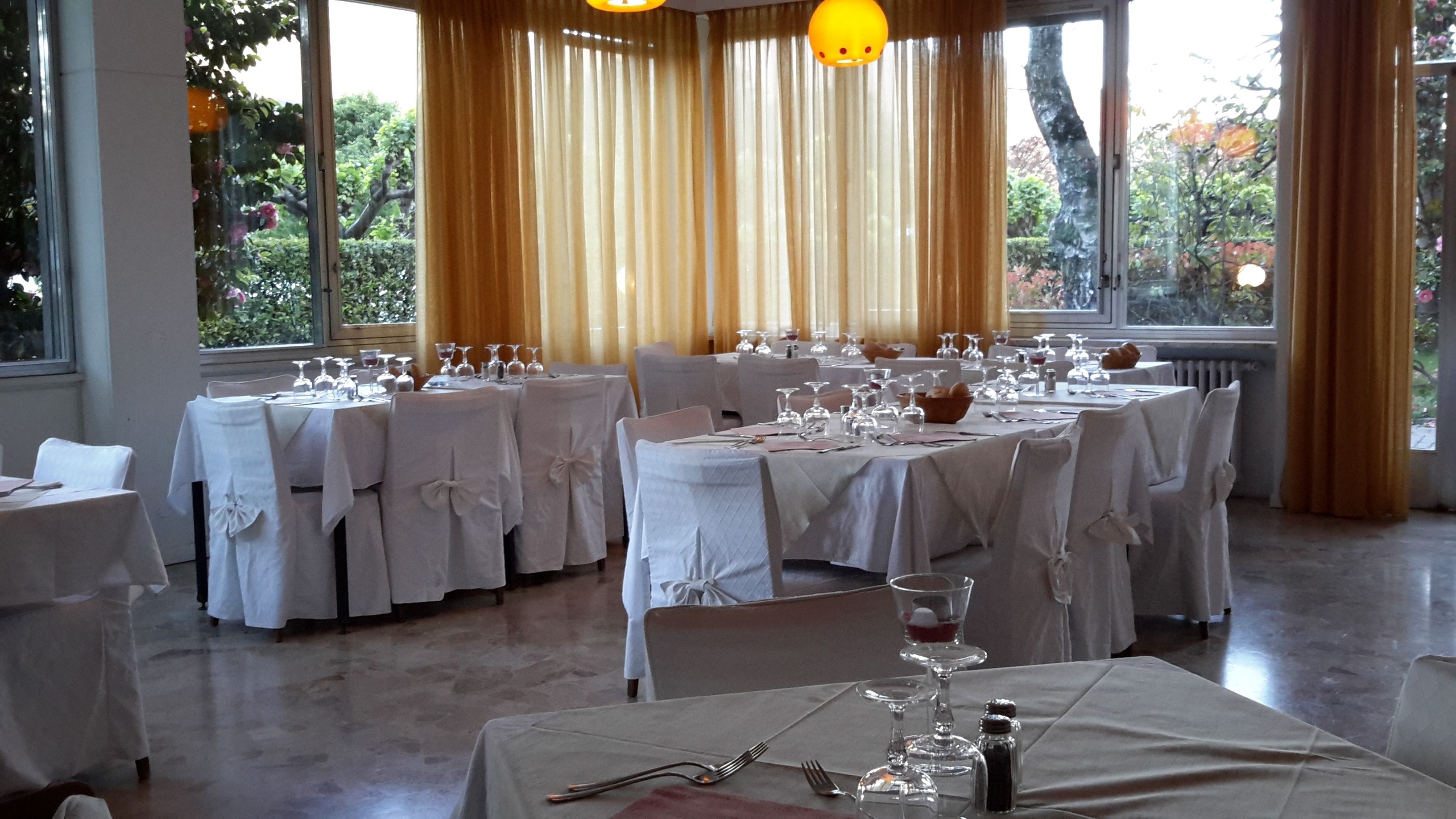 Un salón de banquetes con mesas redondas dispuestas para un evento formal, con manteles blancos y cristalería.