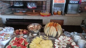 Un bufé con diversas opciones de comida, incluyendo sandía, piña y rodajas de tomate.