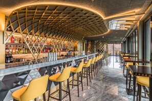A bar area with a curved ceiling, bar stools, and a long counter with various bottles. - Leonardo Hotel London Aldgate - formerly Hotel Saint (London)