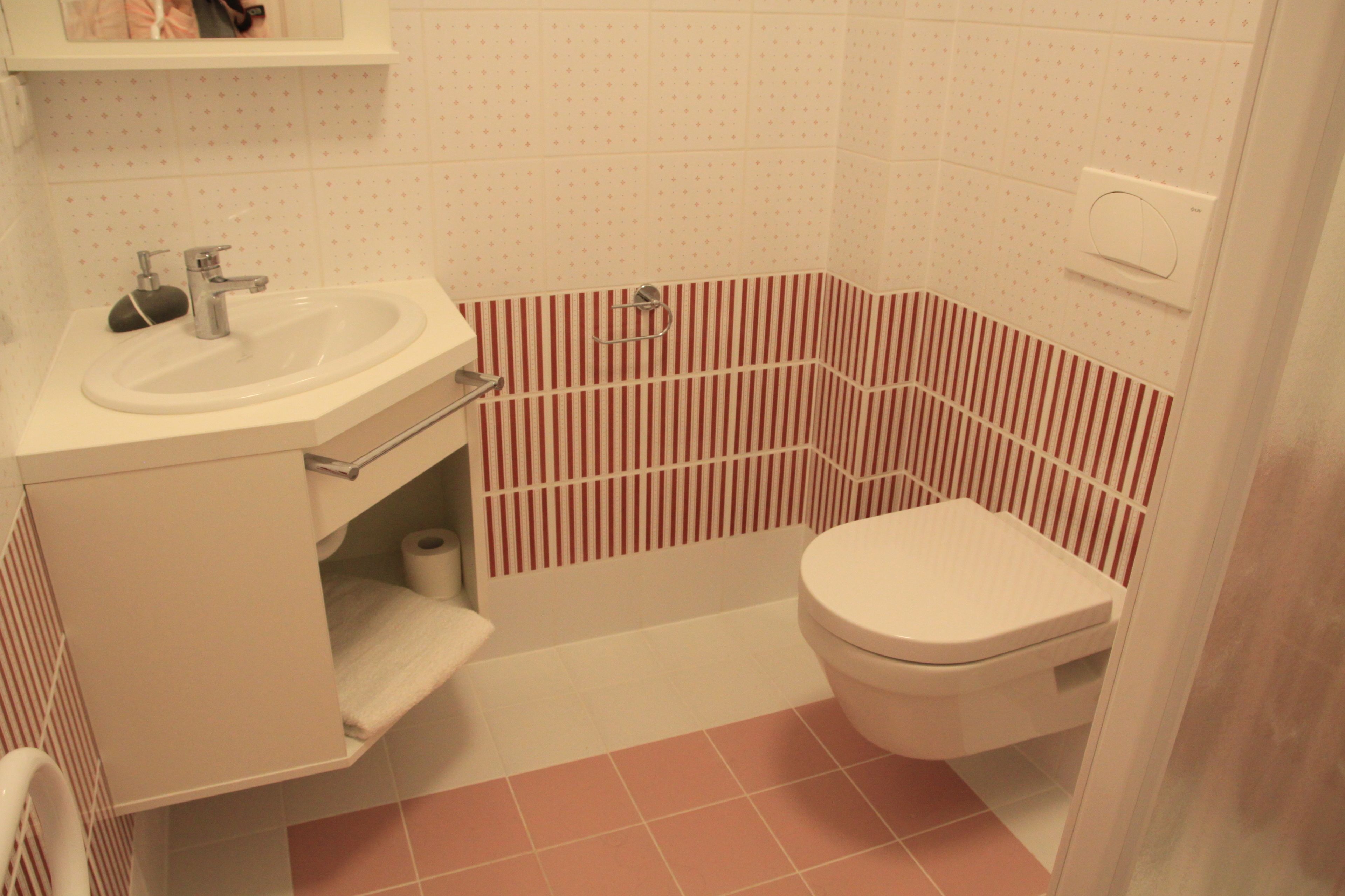 A bathroom with a sink, toilet, and striped wall tiles.