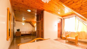 Quarto com cama, poltrona, sofá e janela com cortinas.