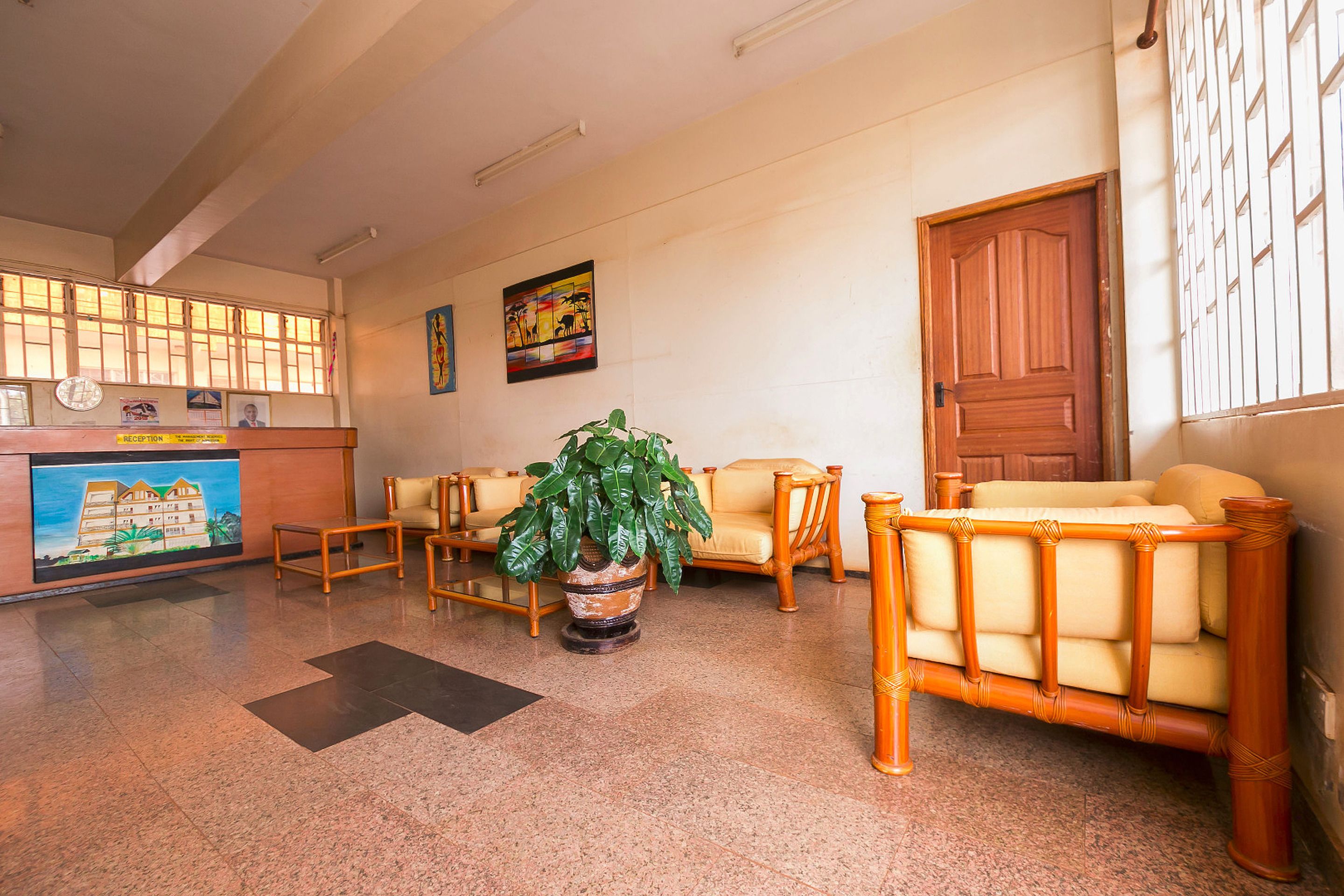 A reception area with a reception desk, a potted plant, and two sofas.