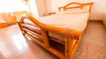A bed with a wooden frame and a woven headboard, a bedside table, and a window with curtains.