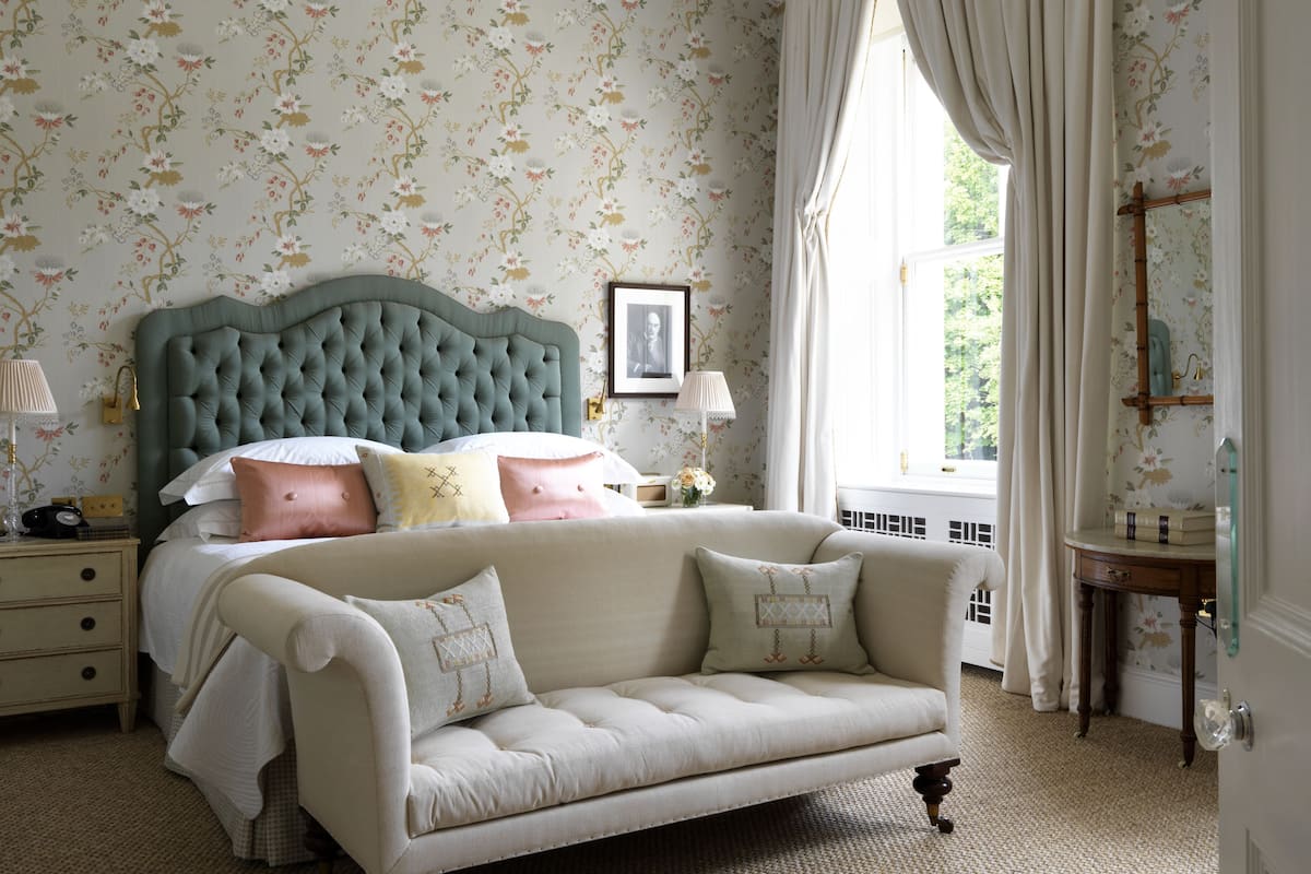 A bedroom with a large bed, a nightstand, a dresser, and a window with curtains.