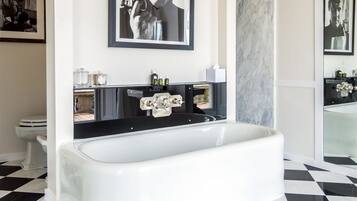 Een moderne badkamer met een zwart-wit geruite vloer, een witte badkuip en een ingelijste foto aan de muur.