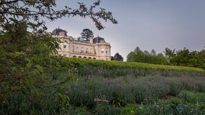 A large, historic building with a symmetrical facade, surrounded by well-maintained gardens and hedges. - Beaverbrook (Leatherhead)